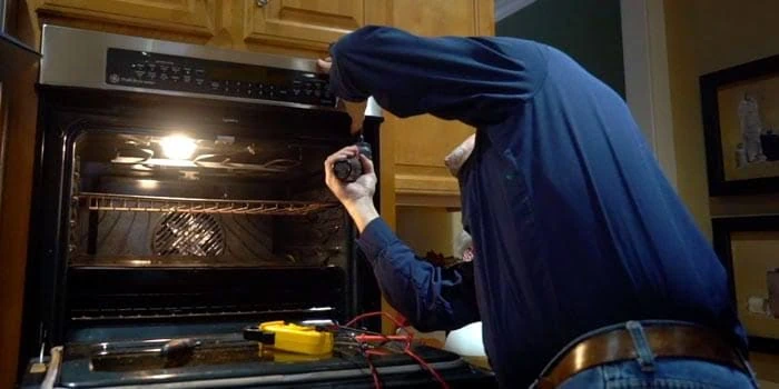Technician inspecting an oven with diagnostic tools